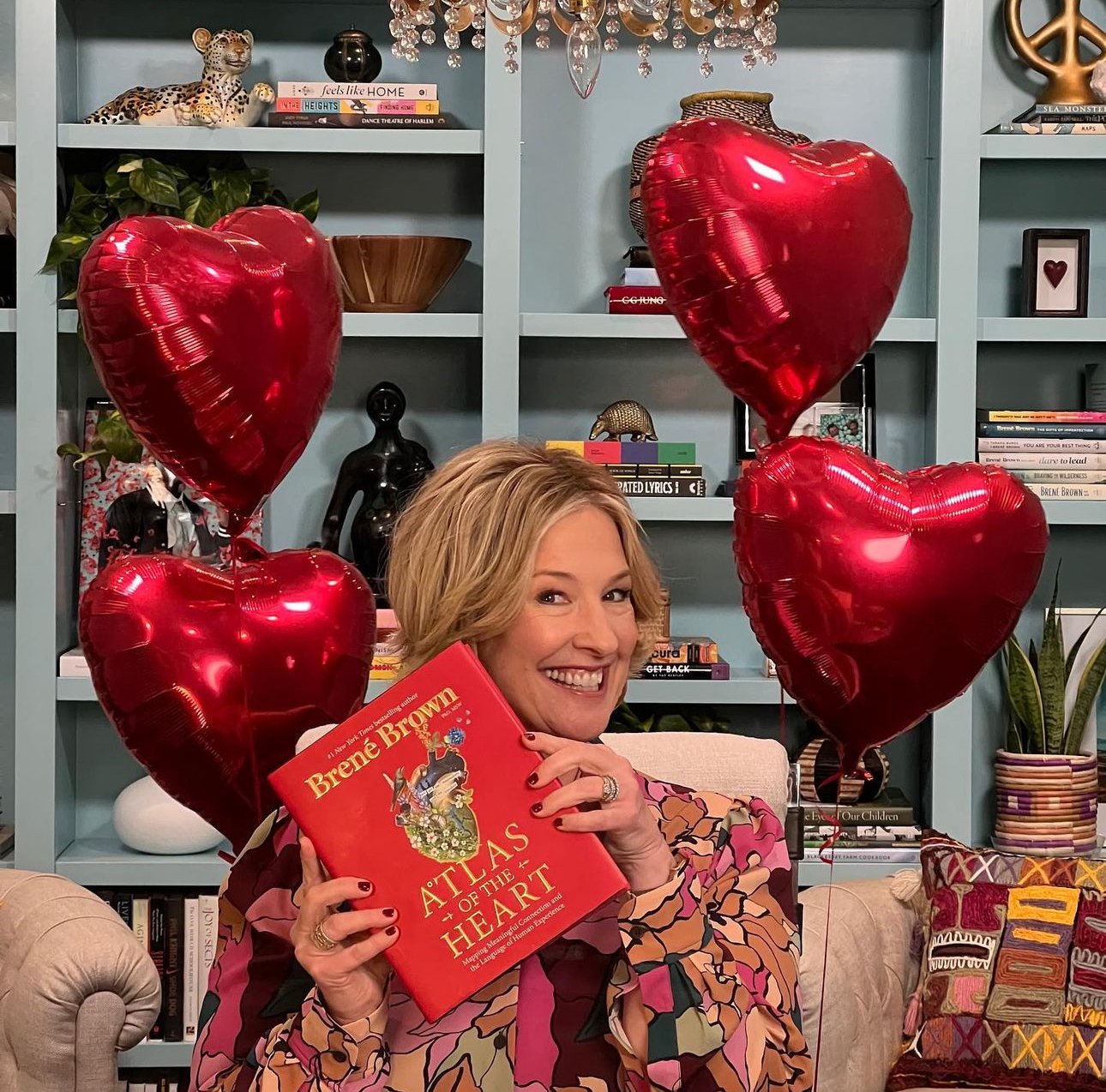 Brené Brown posing with one of her books, "Atlas of The Heart"
