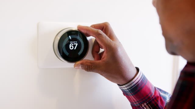 A person adjusting their smart thermostat 