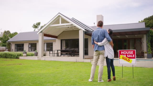 A couple standing in front of a house they just purchased