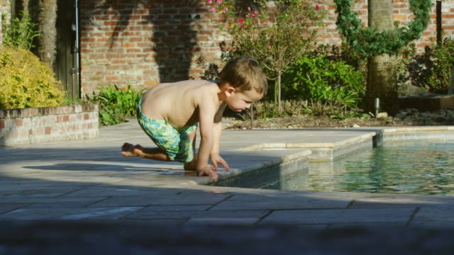 A little boy playing next to a pool