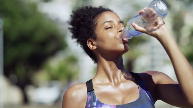 A lady working out and drinking water.