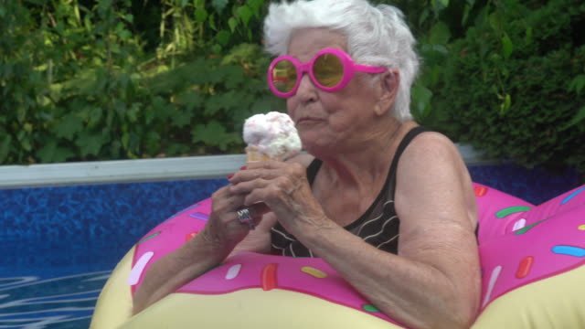 A grandma eating ice cream,  wearing pink glasses floating on a floaty