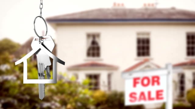 A silhouette of a house key chain in front of a house listed for sale. 