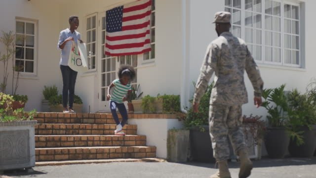 A military family welcoming the father in fatigues home. 