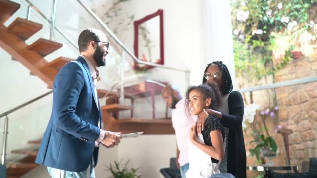 A black Real Estate agent sowing a black family around a new modern home.