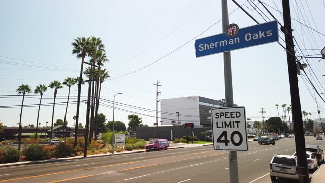 The Sherman Oaks street sign, with a 40 MPH street sign, with palm trees in the background.
