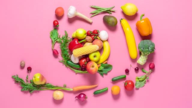 A mix of fruits and vegetables with a pink background