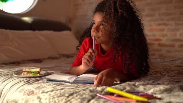 A young black girl journaling.  