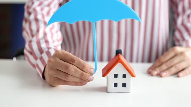 Person holding an umbrella over a home