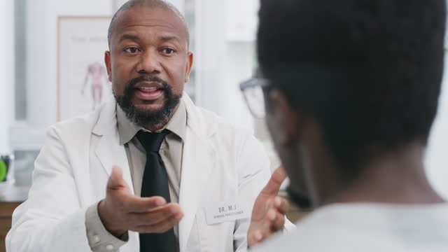 A black male doctor having a stern conversation with his black male patient 