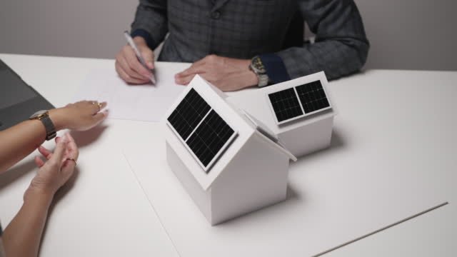Miniature houses that are white with solar panels on top of them.