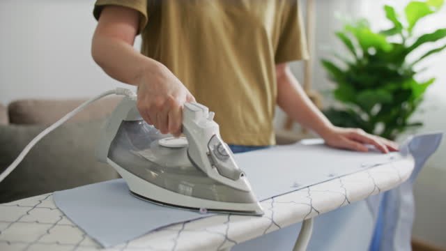 A person ironing their shirt with an iron.