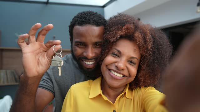 A black couple holding up keys to their first home 