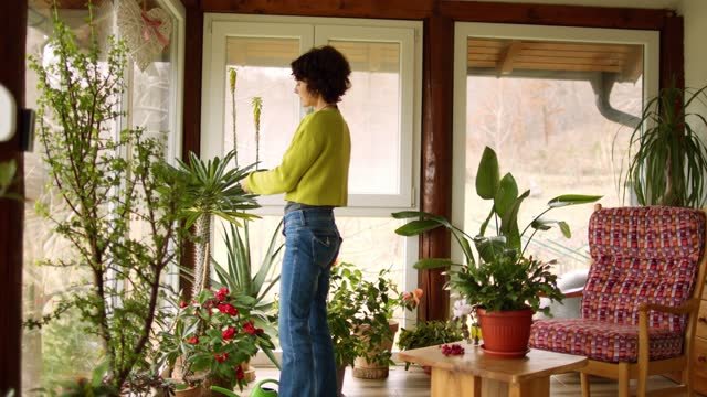 A white lady caring for her indoor plants.  