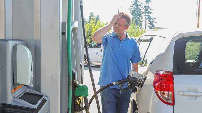 A white male frustrated at the gas prices while pumping his gas