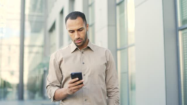 A black male looking at an app on his phone. 