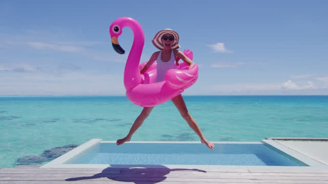 A woman jumping in the air with a pink flamingo floatie 