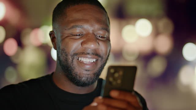 A man smiling while looking at his phone