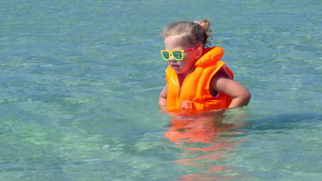 A little girl with orange floaties on in the pool.