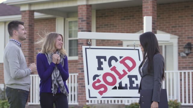 Family standing in front of a sold house
